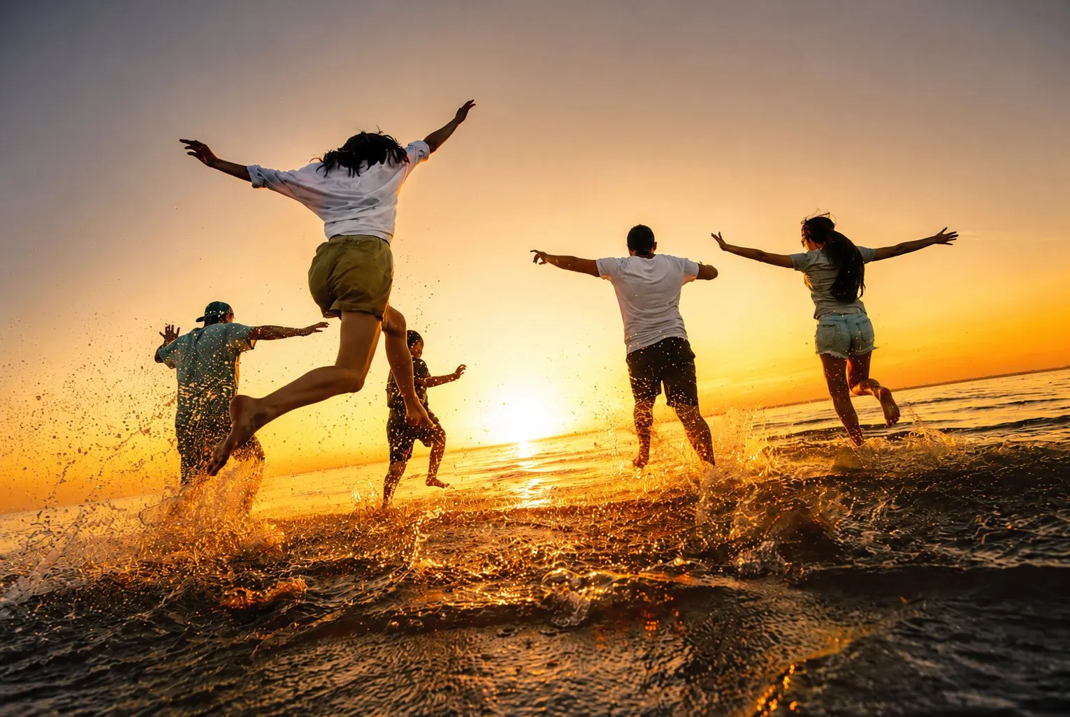 Friends jumping for joy on the beach at sunset