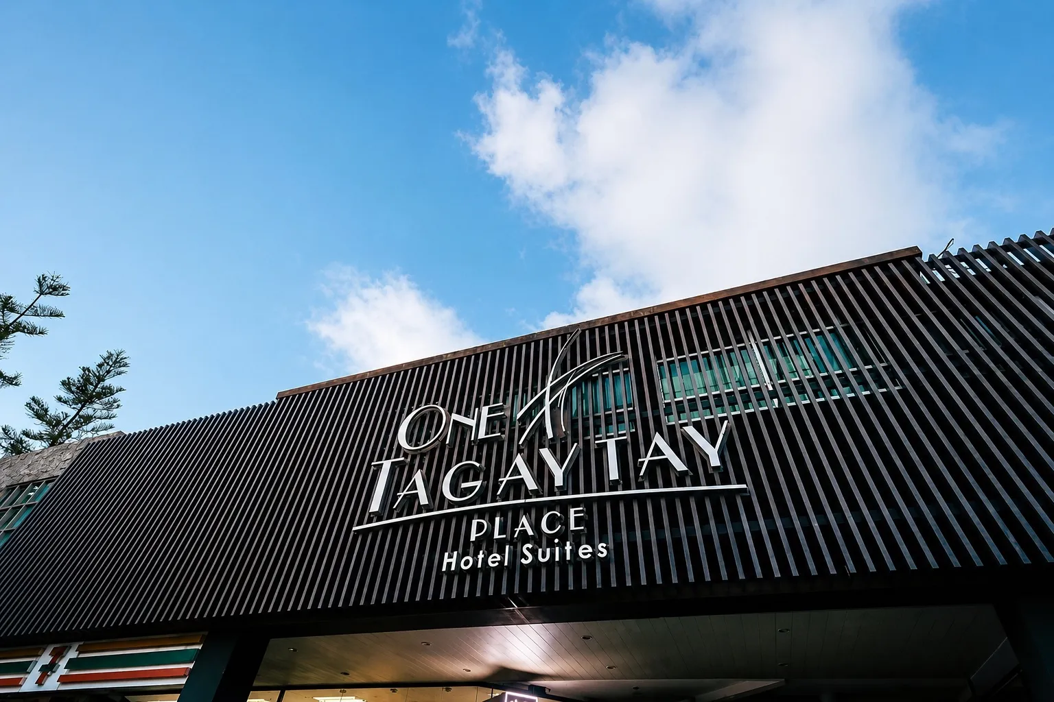 The One Tagaytay Place Hotel Suites sign against a blue sky