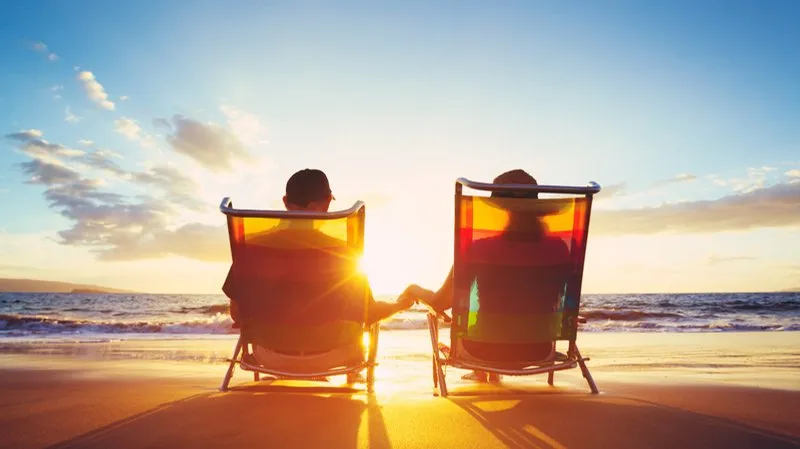 A couple relaxing in beach chairs, watching the sun set over the sea
